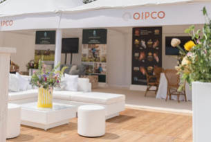 White sofas wooden flooring outdoor hospitality area poster of racehorses in background in white tent