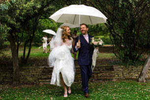 Bridal couple under an umbrella in a garden